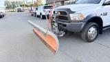 A 2016 RAM 5500 truck equipped with a mounted snow plow positioned in the foreground ready for use