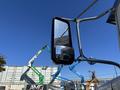A 2020 Peterbilt 330 truck with a prominent side mirror reflecting nearby construction equipment