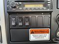 Dashboard controls of a 2012 International DuraStar 4300 featuring a radio display and several switches for vehicle functions including warning and maintenance instructions