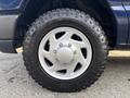 Close-up of a silver alloy wheel on a 2013 Ford E-350 Super Duty featuring a rugged off-road tire with deep treads