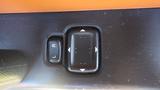 A control button for the side mirrors featuring directional arrows and labels for left and right on a textured surface