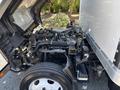 A 2022 Isuzu NRR with the hood lifted revealing the engine compartment featuring various pipes and components arranged over the engine block