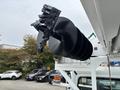 A black auger attachment mounted on a vehicle designed for industrial use, featuring several spiral blades for digging or drilling applications