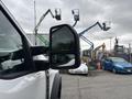 A white 2023 Ford F-450 Super Duty with a side mirror reflecting nearby machinery and equipment