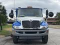 A 2013 International DuraStar 4300 truck with a blue and white color scheme features large chrome grilles and dual side mirrors