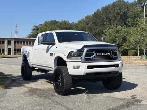 A lifted white 2018 RAM 3500 truck with a black grille oversized tires and a muscular stance positioned in the foreground