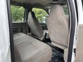 Interior view of a 2010 Ford F-550 Super Duty showing two front seats and a spacious rear bench seat upholstered in light gray fabric
