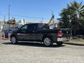 Black 2015 RAM 1500 truck parked with chrome accents and a rear bed cover